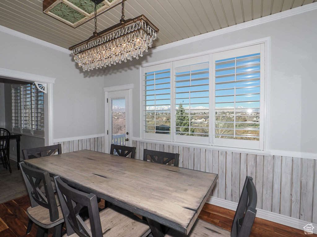 Dining space with a notable chandelier, crown molding, and dark hardwood / wood-style flooring