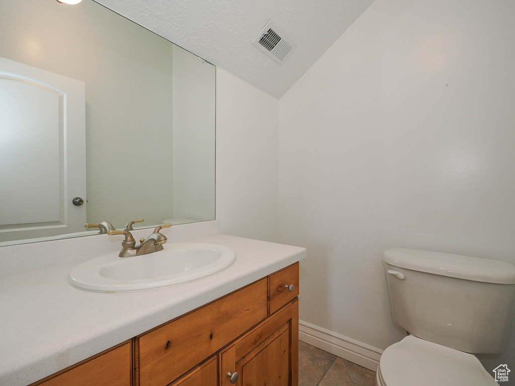 Bathroom featuring vanity, lofted ceiling, tile floors, and toilet