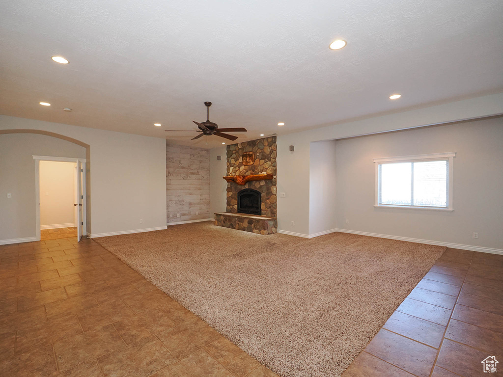 Unfurnished living room featuring ceiling fan, a fireplace, and light tile floors