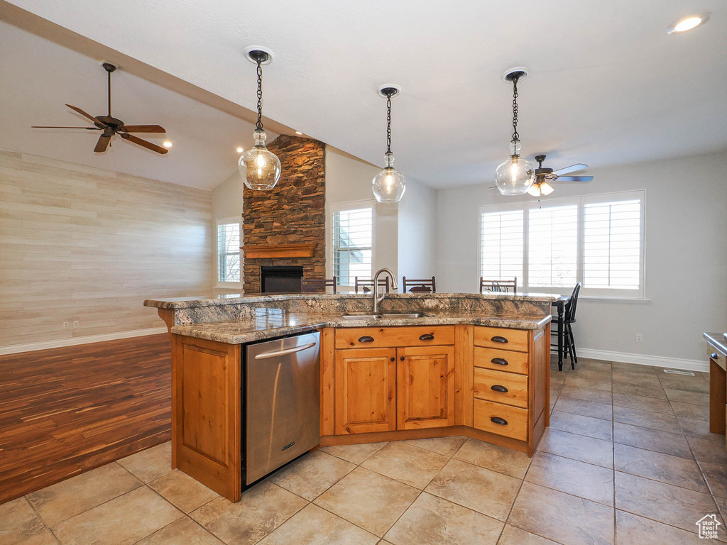 Kitchen with a stone fireplace, dishwasher, ceiling fan, and light wood-type flooring