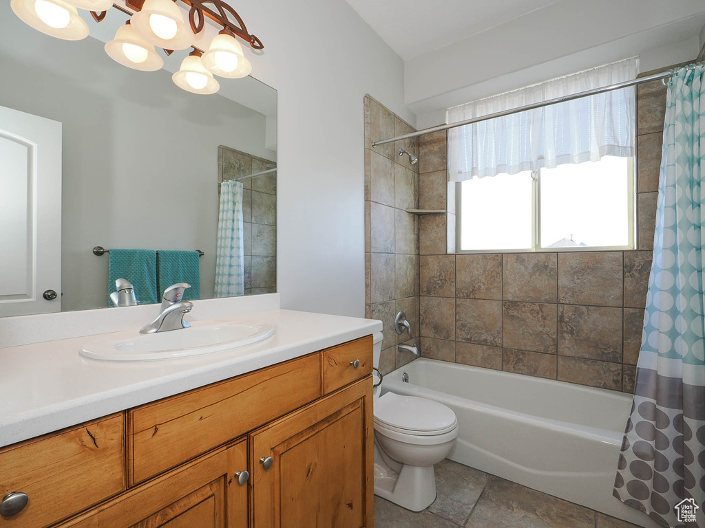 Full bathroom with toilet, shower / bath combo, vanity, tile flooring, and an inviting chandelier