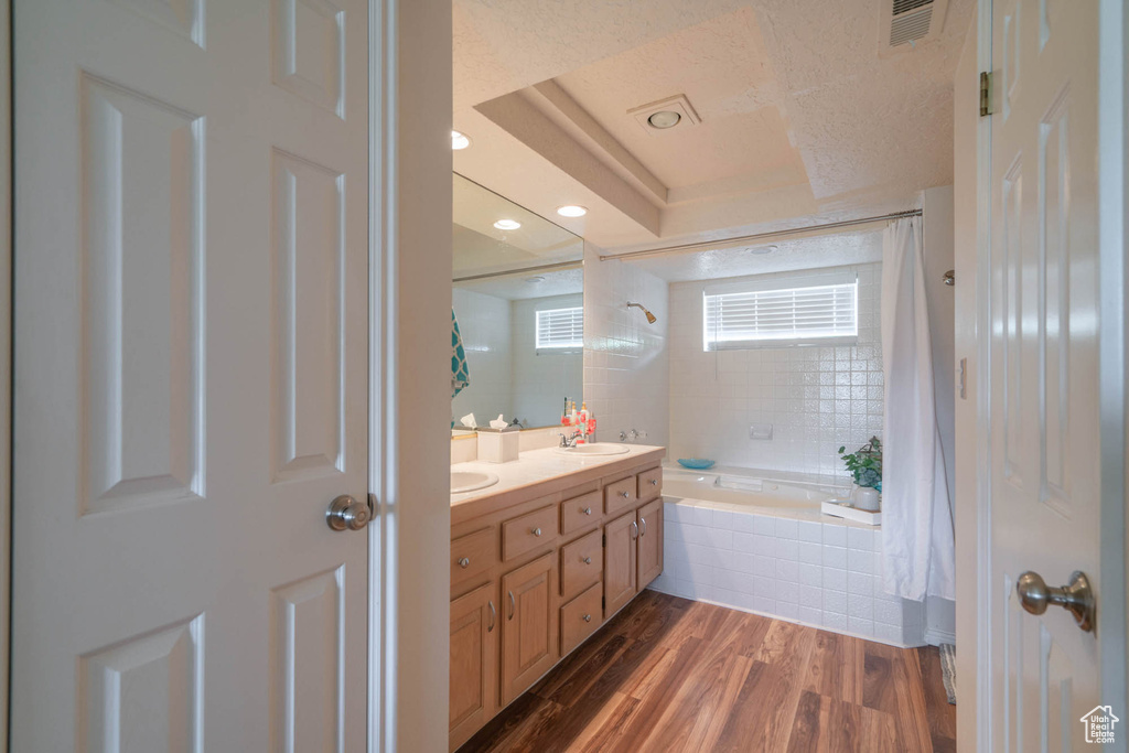 Bathroom with hardwood / wood-style floors, a textured ceiling, and dual vanity