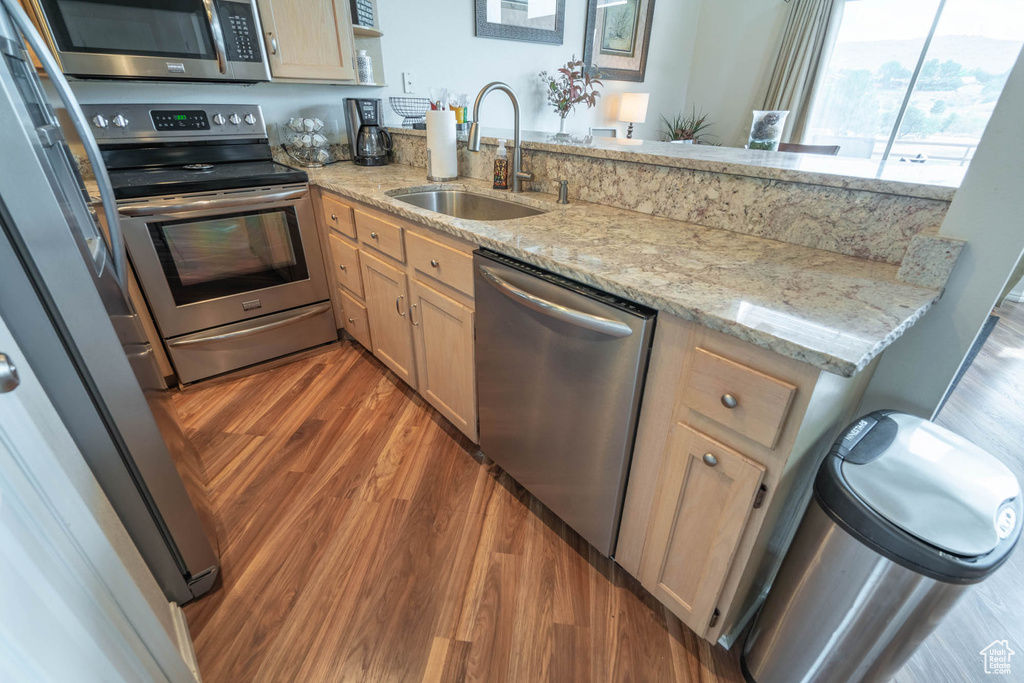 Kitchen featuring light stone counters, light hardwood / wood-style floors, stainless steel appliances, and sink