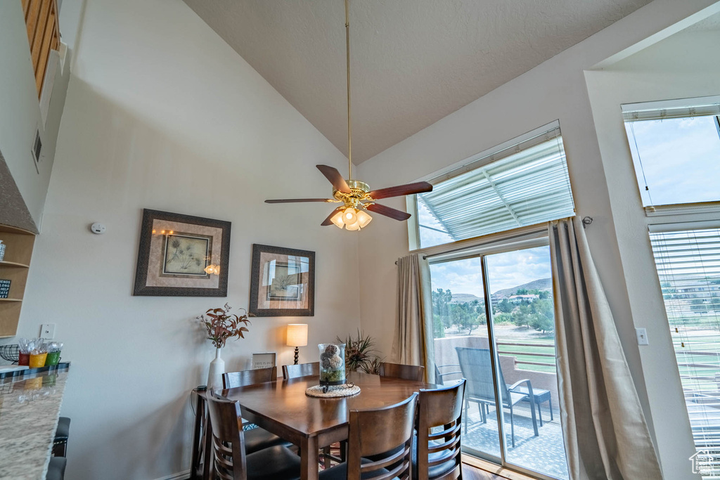 Dining space featuring ceiling fan and high vaulted ceiling