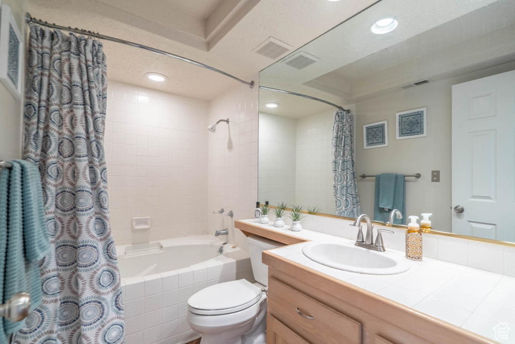 Full bathroom with toilet, large vanity, and shower / bath combo