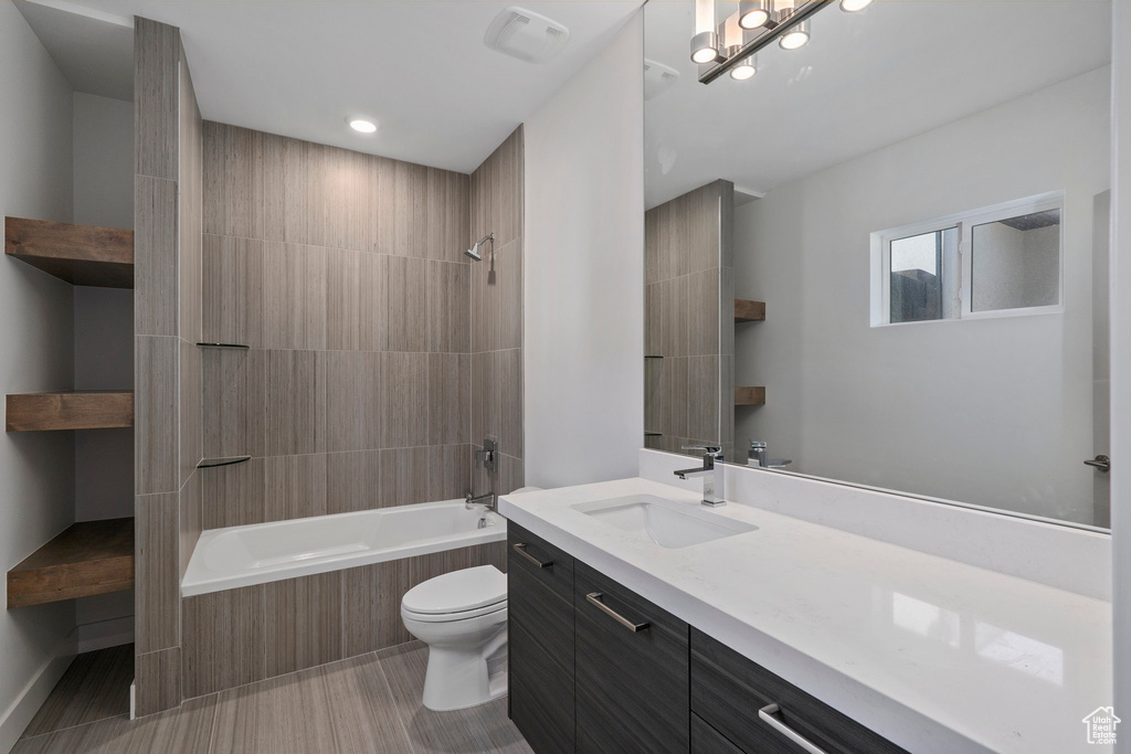 Full bathroom with tile floors, vanity, toilet, and tiled shower / bath