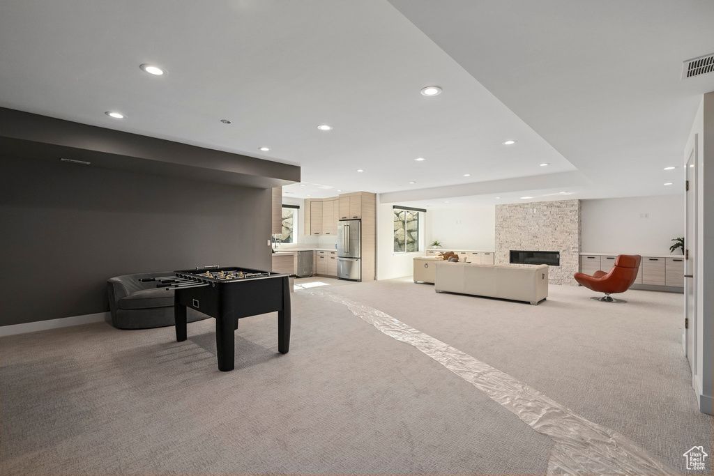 Recreation room featuring light carpet and a stone fireplace