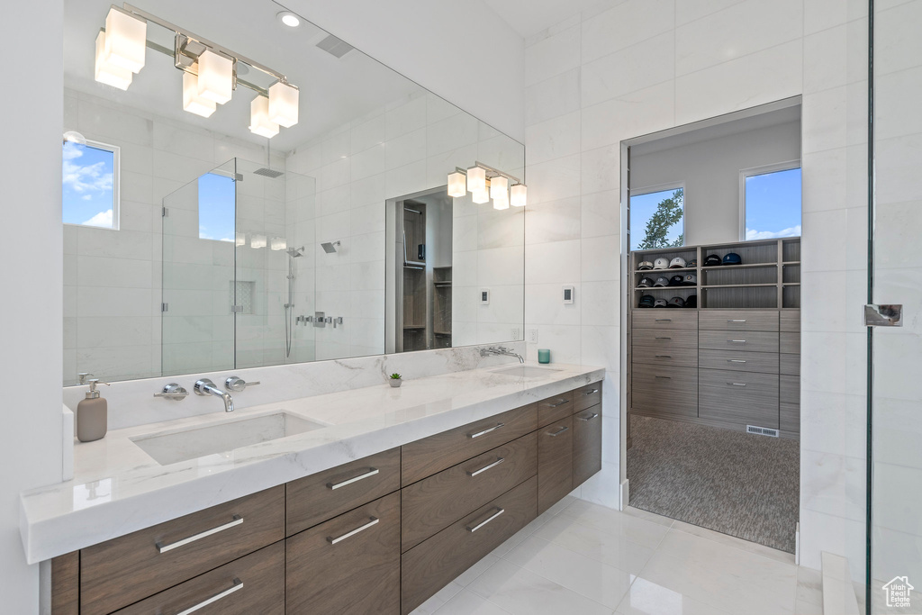 Bathroom featuring plenty of natural light, tile walls, tile flooring, and vanity with extensive cabinet space