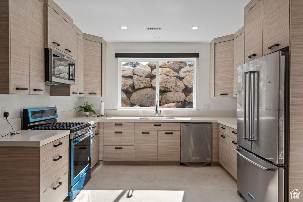 Kitchen with light tile flooring, light brown cabinets, and appliances with stainless steel finishes