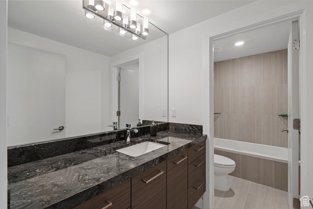 Full bathroom with tile flooring, toilet, tiled shower / bath combo, and vanity