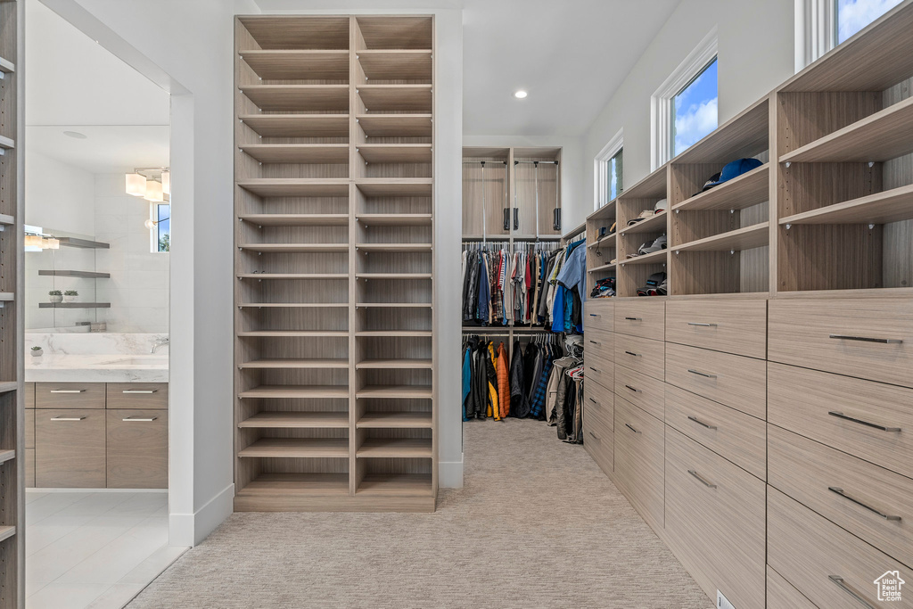 Spacious closet featuring a notable chandelier and light carpet