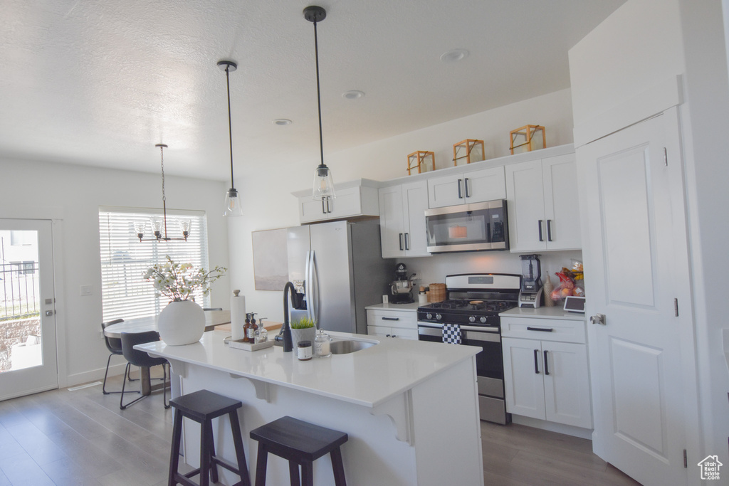 Kitchen with hanging light fixtures, an inviting chandelier, a breakfast bar, an island with sink, and stainless steel appliances