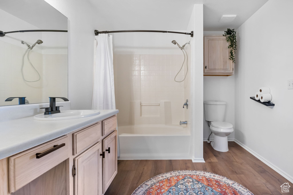 Full bathroom featuring shower / tub combo with curtain, vanity, toilet, and hardwood / wood-style flooring