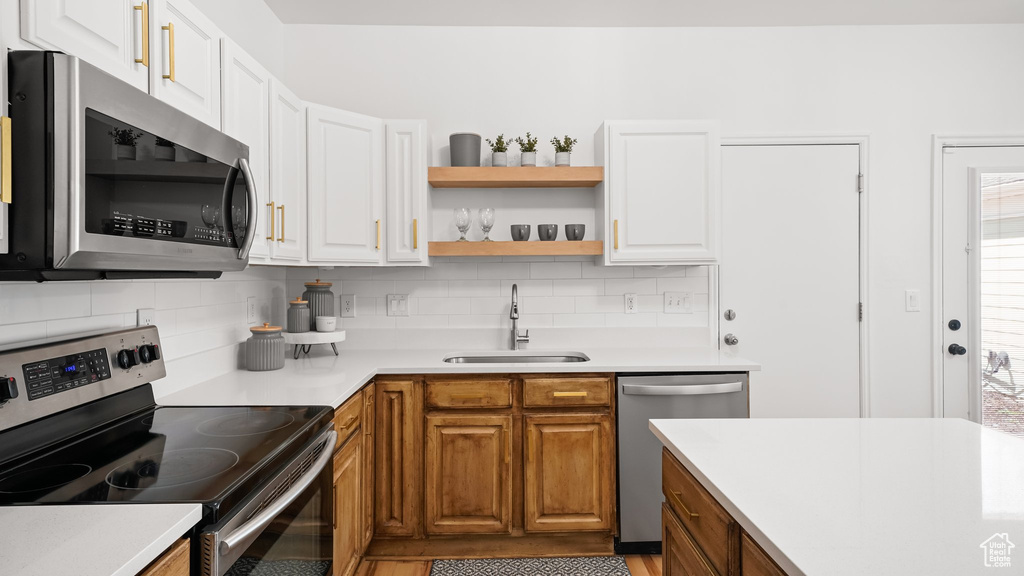 Kitchen featuring white cabinets, backsplash, stainless steel appliances, and sink