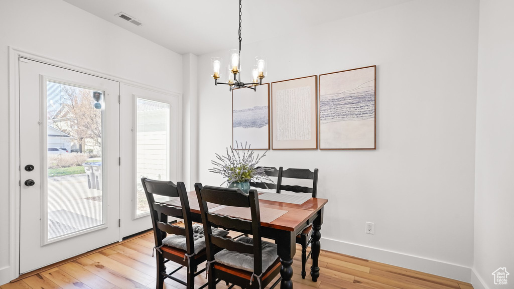 Dining space featuring an inviting chandelier, a wealth of natural light, and light wood-type flooring