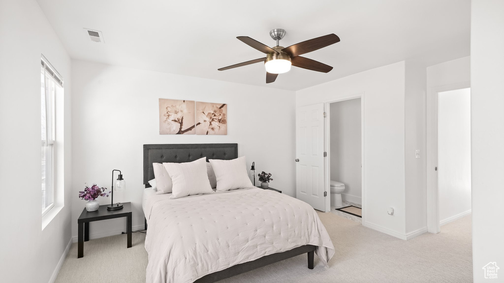 Bedroom featuring light carpet, ensuite bathroom, and ceiling fan