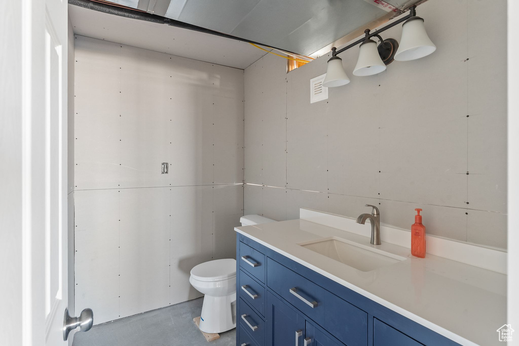 Bathroom featuring toilet, concrete flooring, and large vanity