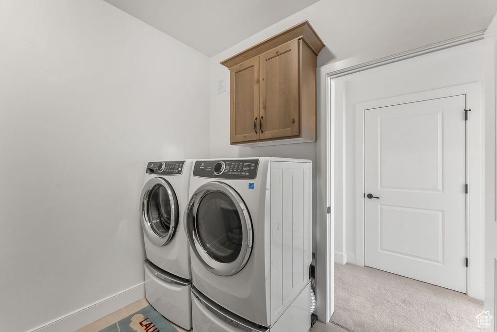 Washroom featuring cabinets, light colored carpet, and washer and dryer