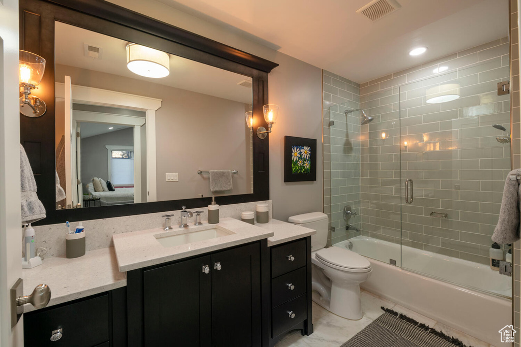 Full bathroom featuring toilet, shower / bath combination with glass door, tile floors, and vanity