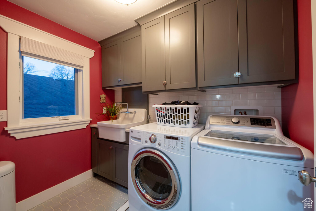 Clothes washing area with light tile floors, separate washer and dryer, cabinets, hookup for a washing machine, and sink
