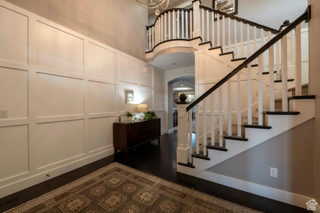 Entryway featuring dark hardwood / wood-style flooring, an inviting chandelier, and a towering ceiling