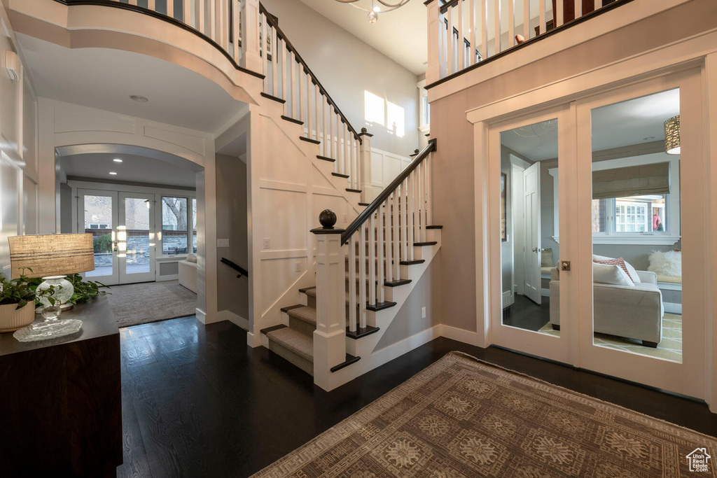 Staircase with dark hardwood / wood-style flooring, a high ceiling, and french doors