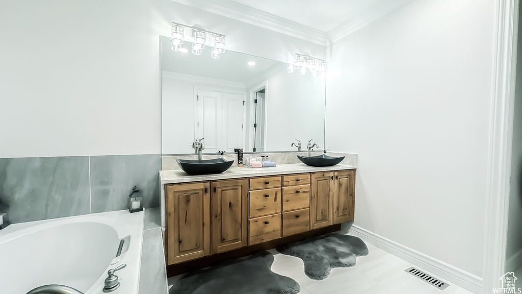 Bathroom featuring crown molding, double sink vanity, and a washtub