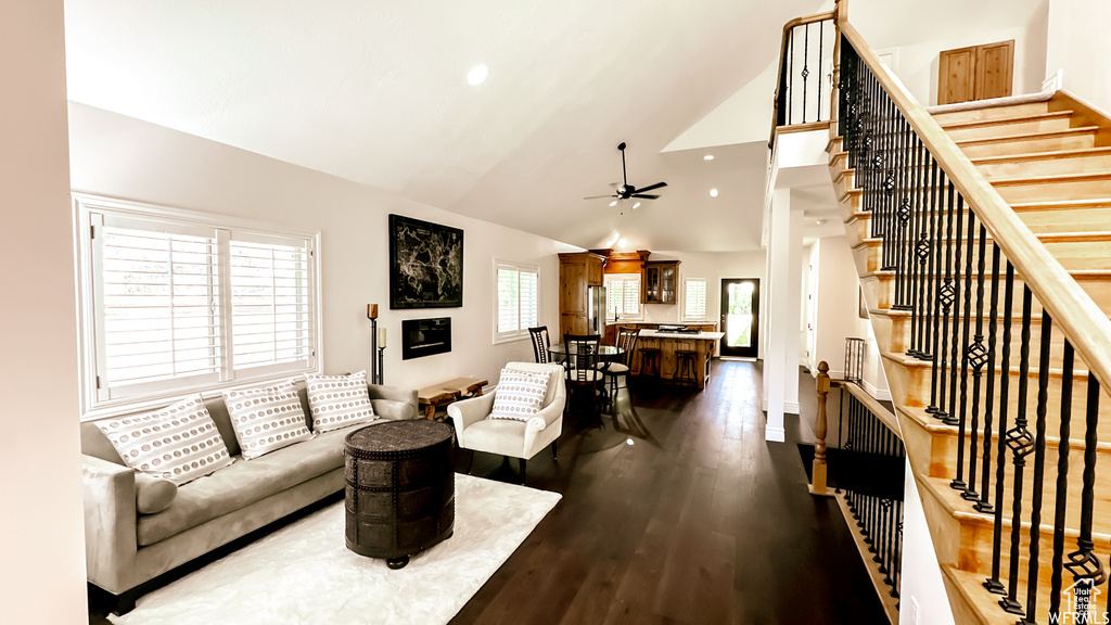 Living room featuring dark wood-type flooring, ceiling fan, and high vaulted ceiling
