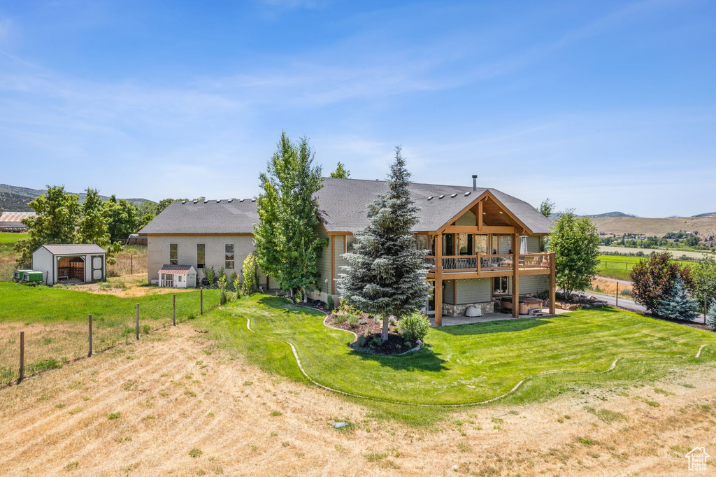 Back of house featuring a yard, a wooden deck, and an outbuilding