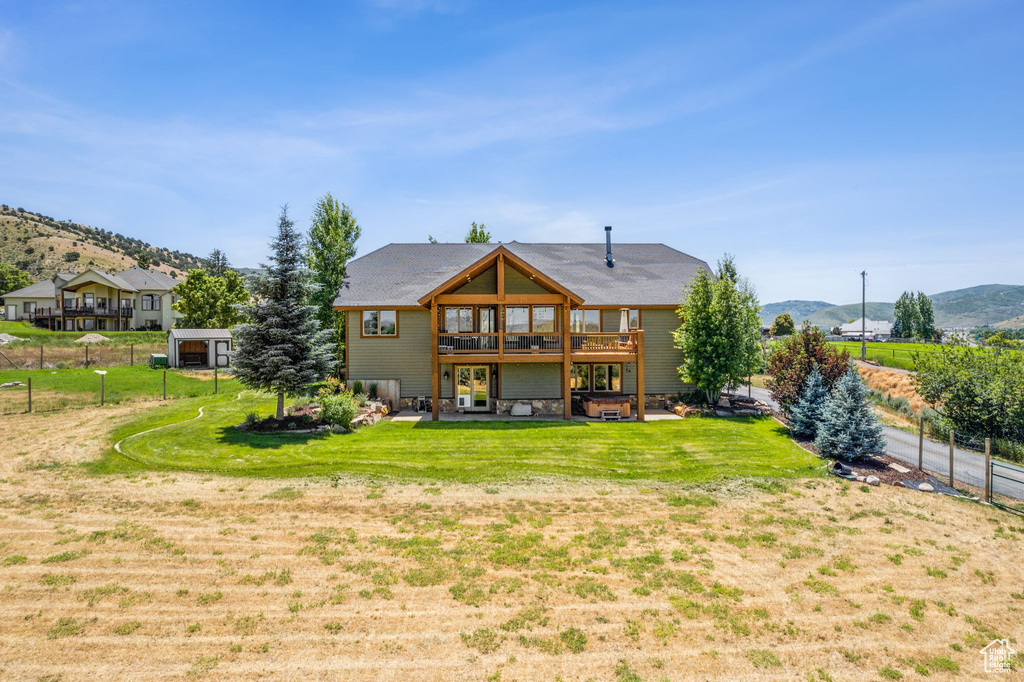 Back of property featuring a deck with mountain view and a yard