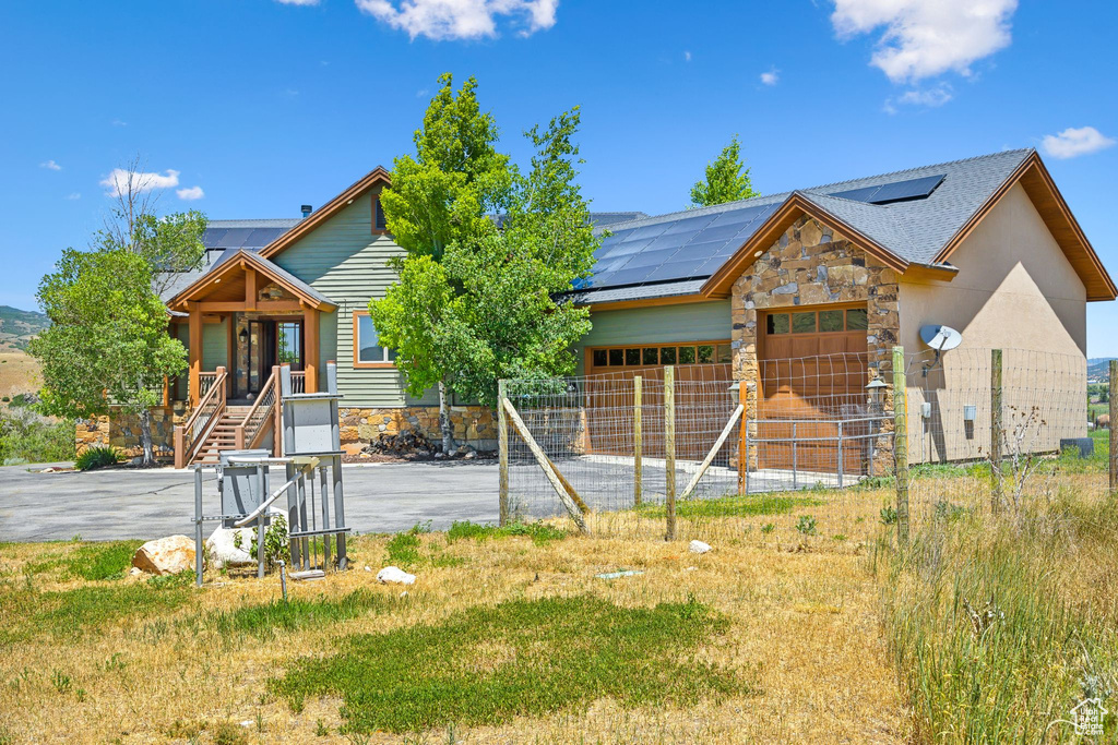 View of front facade featuring a garage and solar panels