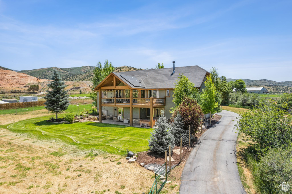 Back of property featuring a mountain view, a balcony, and a yard