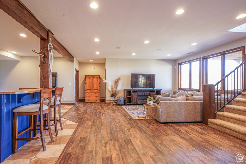 Living room featuring a barn door, beam ceiling, bar, and light hardwood / wood-style flooring