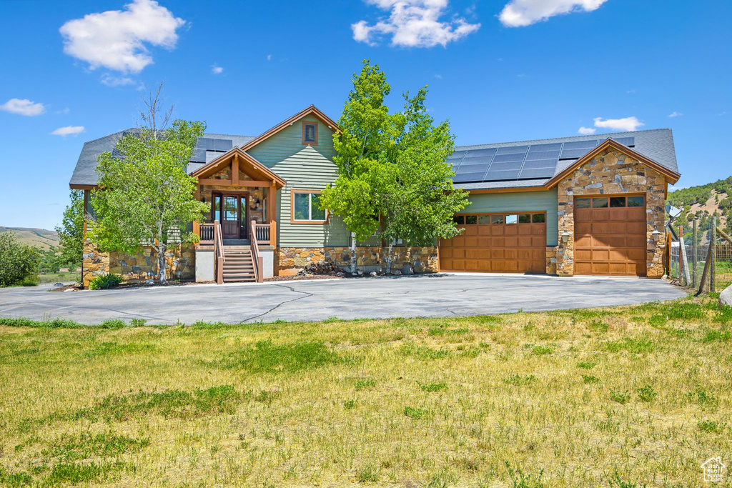 View of front of property featuring a garage, solar panels, and a front yard