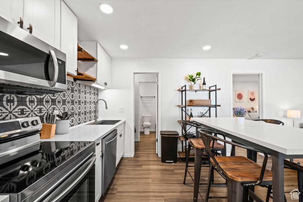 Kitchen featuring white cabinetry, dark wood-type flooring, sink, and stainless steel appliances