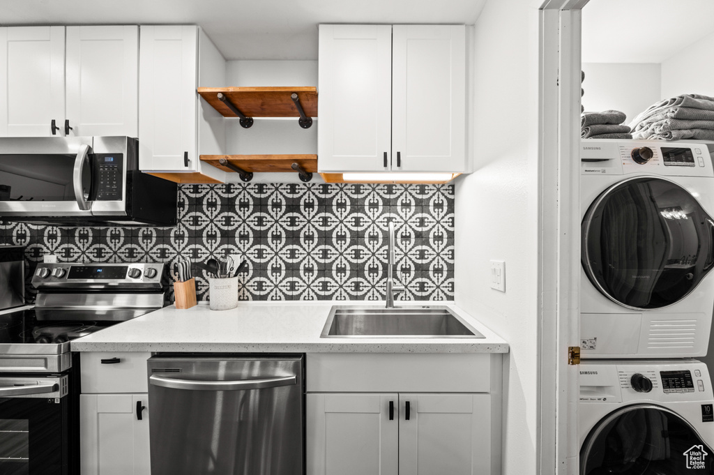Kitchen featuring backsplash, stainless steel appliances, and white cabinetry