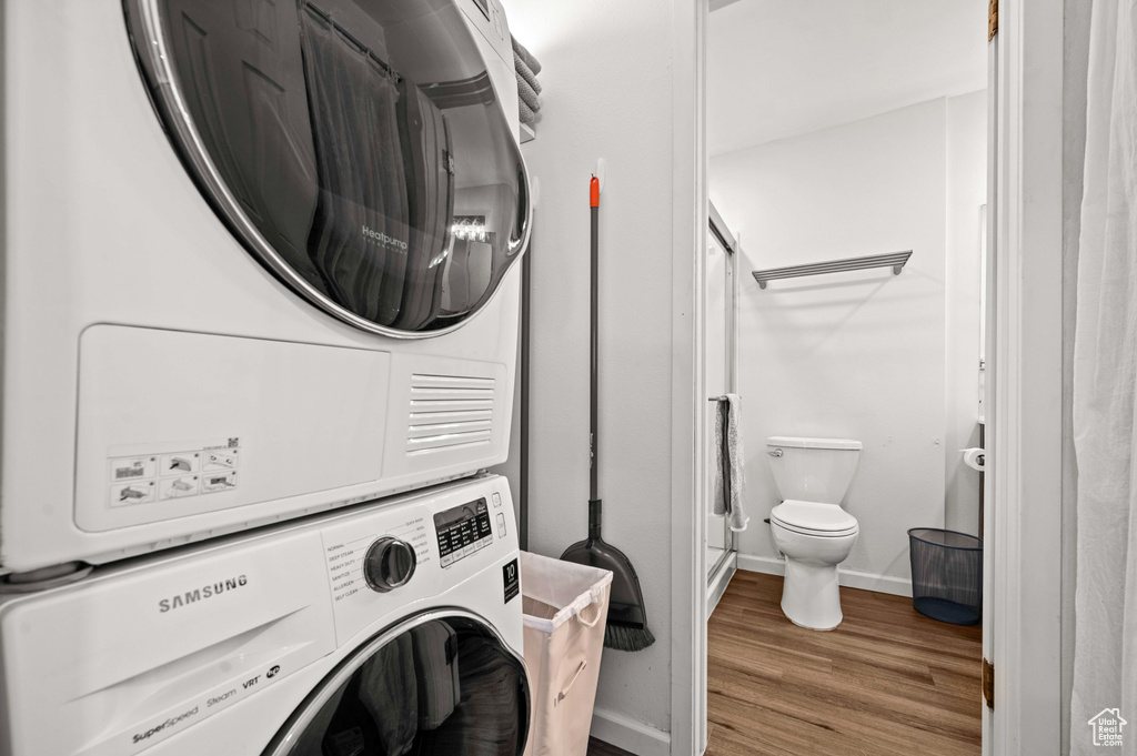 Laundry room with light hardwood / wood-style flooring and stacked washer and clothes dryer