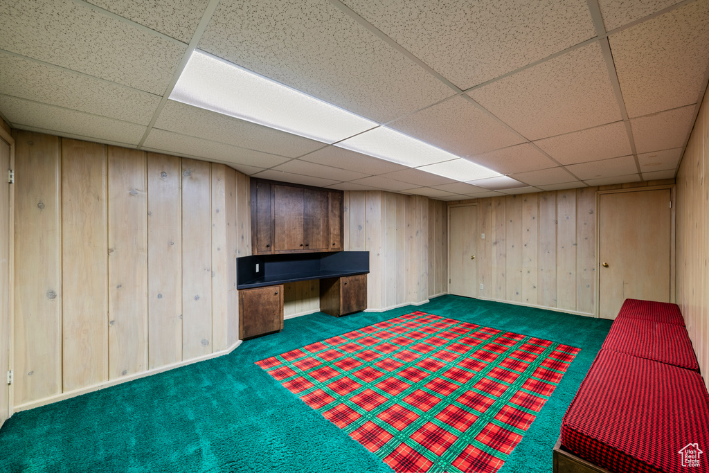 Game room featuring wood walls, dark colored carpet, and a drop ceiling