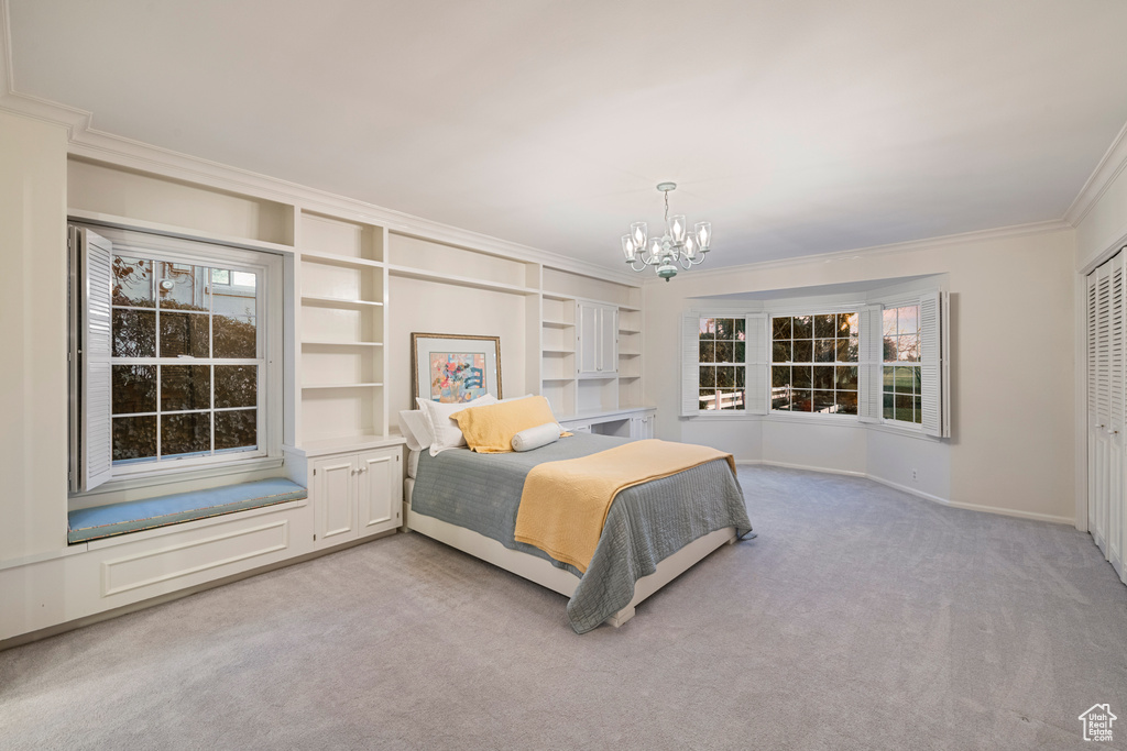Carpeted bedroom with a chandelier, a closet, ornamental molding, and multiple windows