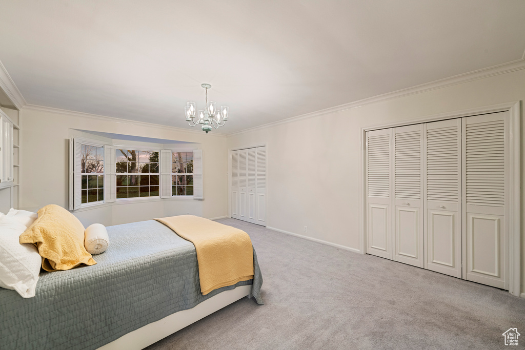 Bedroom with light colored carpet, crown molding, and an inviting chandelier