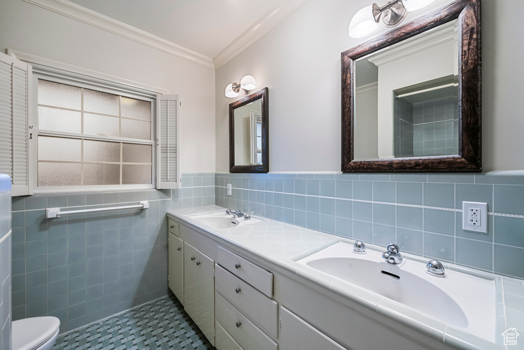 Bathroom with dual vanity, tile walls, tile floors, and toilet