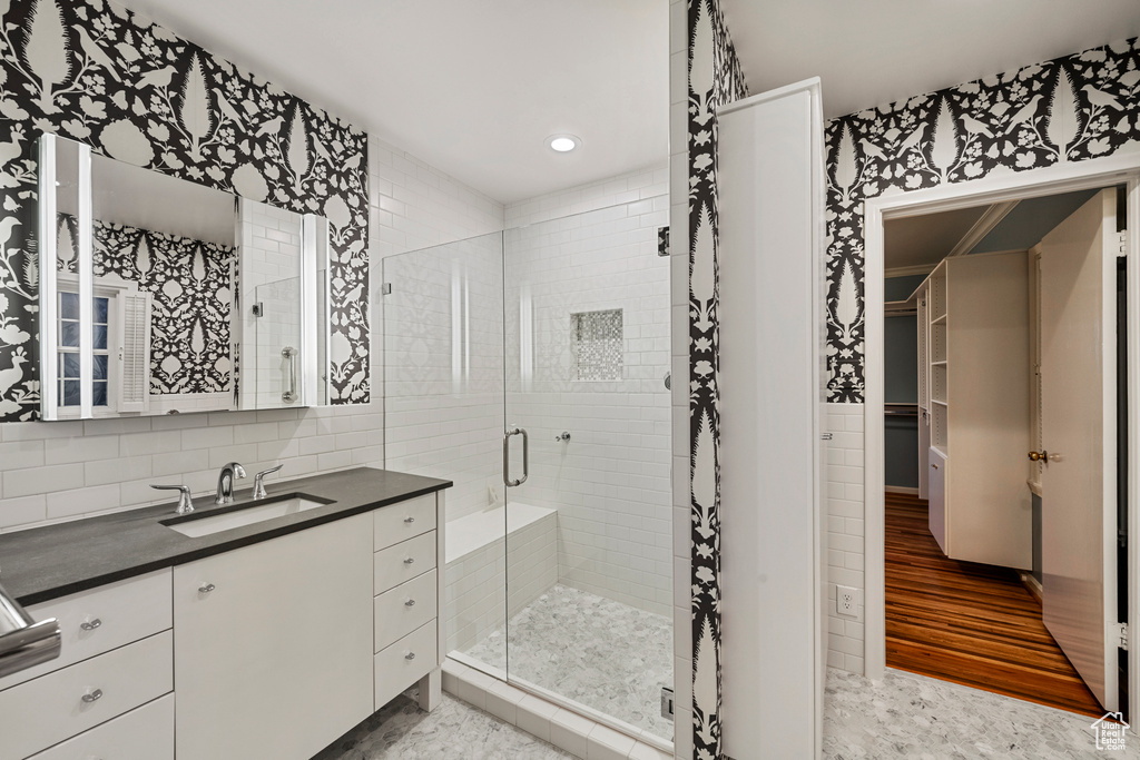 Bathroom featuring backsplash, tile walls, hardwood / wood-style floors, and a shower with door