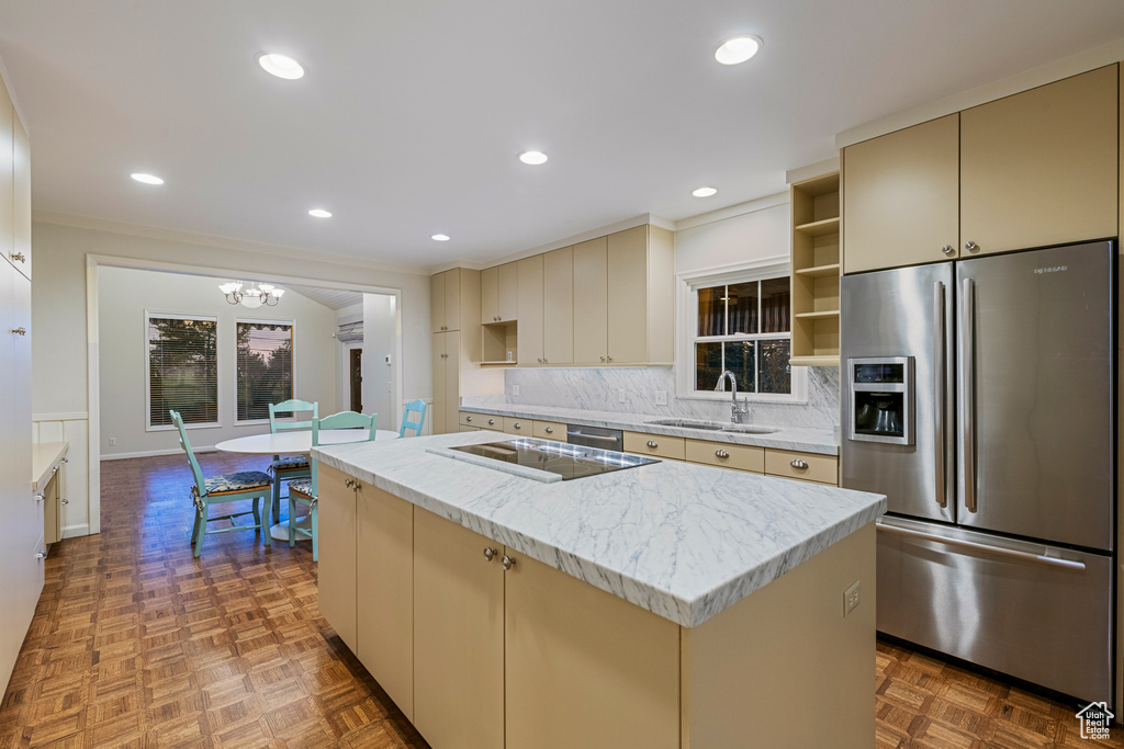 Kitchen with light parquet flooring, tasteful backsplash, stainless steel refrigerator with ice dispenser, a kitchen island with sink, and sink