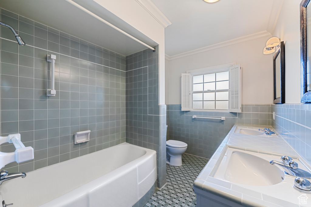 Full bathroom featuring tile walls, tiled shower / bath combo, toilet, and tile flooring