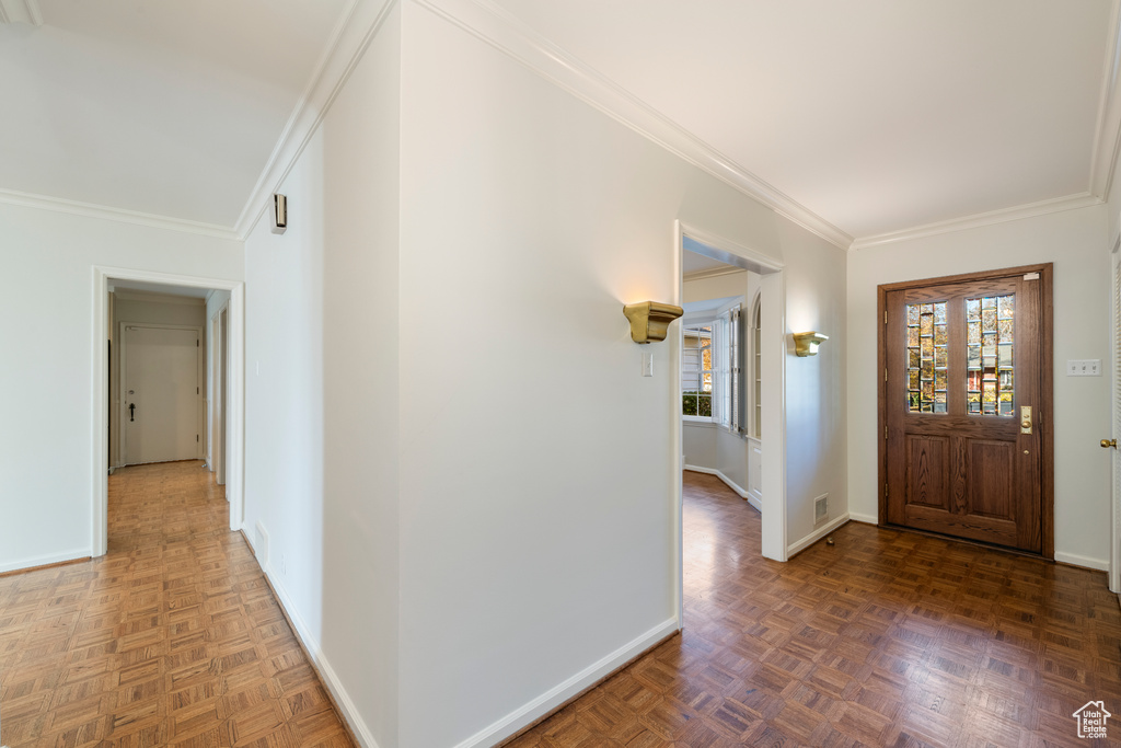 Foyer featuring crown molding and dark parquet floors