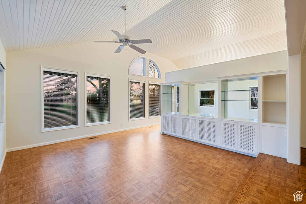 Interior space featuring ceiling fan, built in shelves, parquet floors, and vaulted ceiling