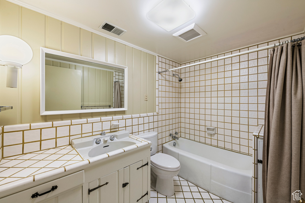 Full bathroom with shower / tub combo with curtain, tile floors, toilet, crown molding, and large vanity