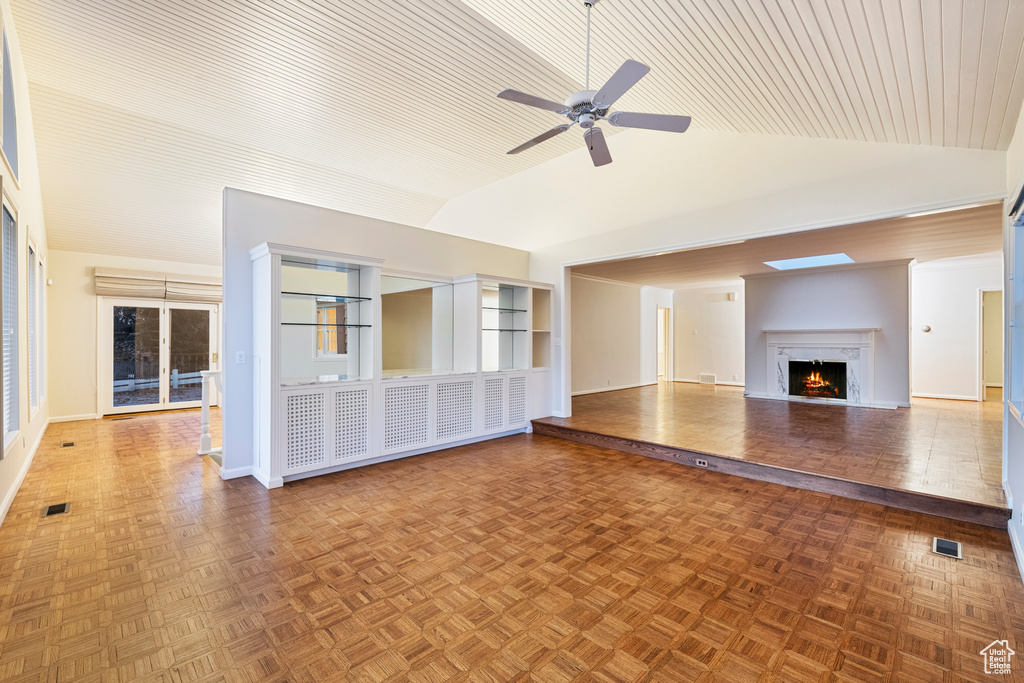 Unfurnished living room with dark parquet flooring, ceiling fan, and vaulted ceiling