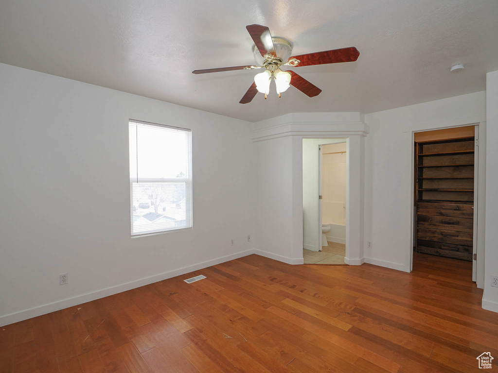 Unfurnished bedroom with ceiling fan, ensuite bathroom, and light hardwood / wood-style floors