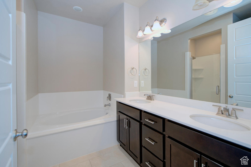 Bathroom with independent shower and bath, large vanity, dual sinks, and tile flooring